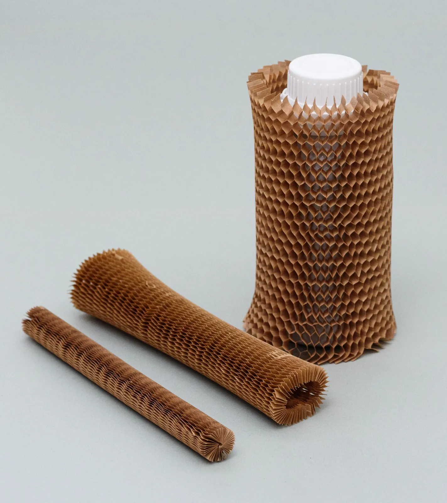 Tubo de papel nido de abeja protegiendo un bote con tapón blanco
